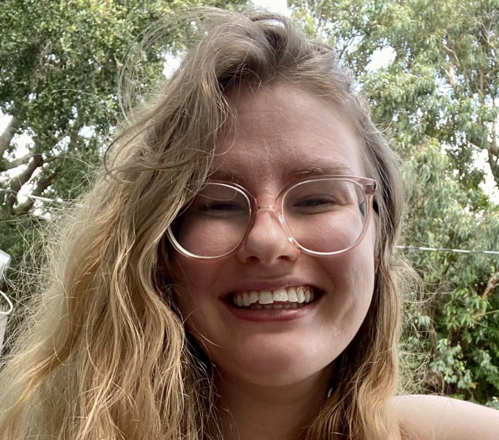 A woman with long hair, wearing glasses and a black top